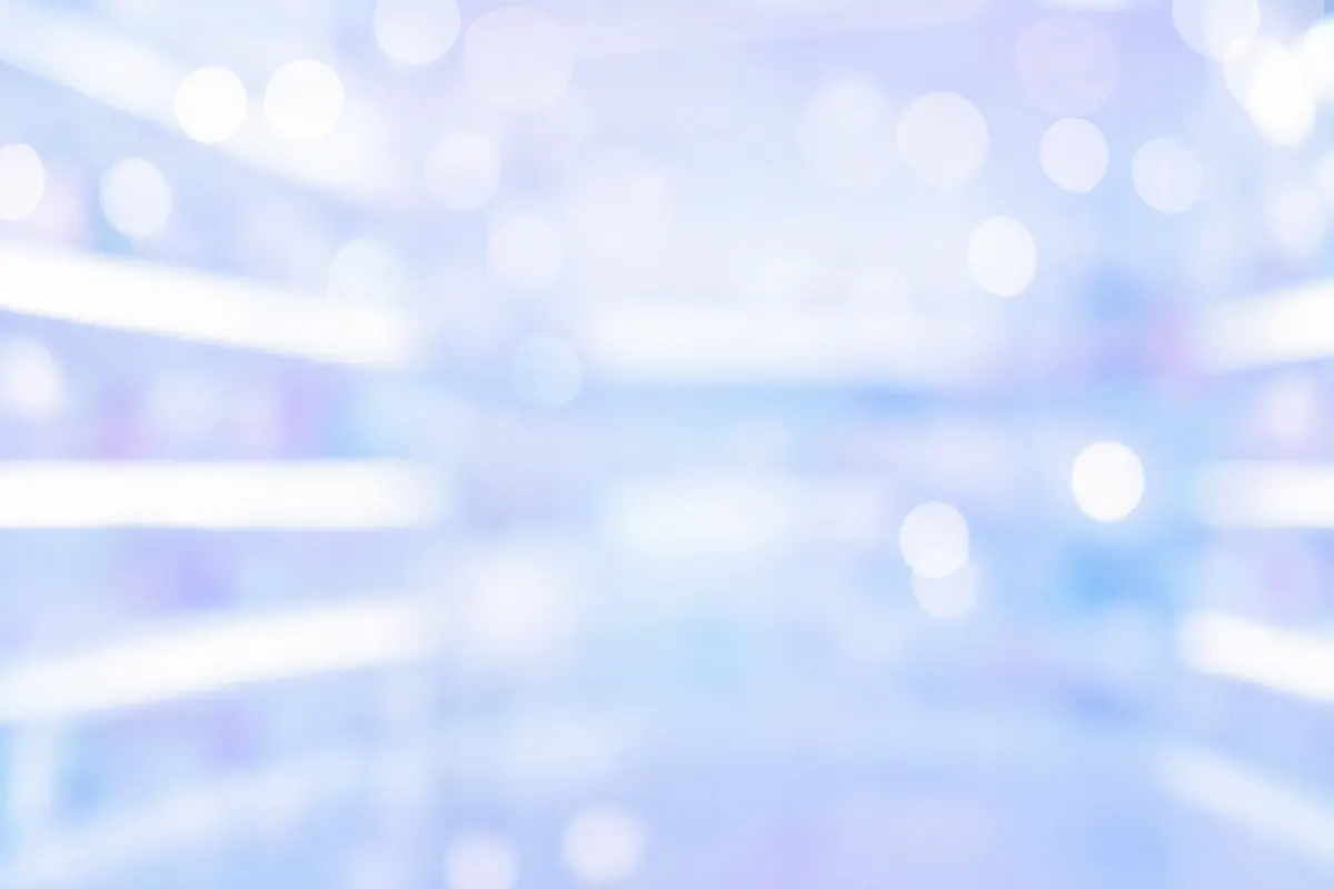 Soft blurred bokeh of bright pharmacy shelves in white, lavender and sky blue
